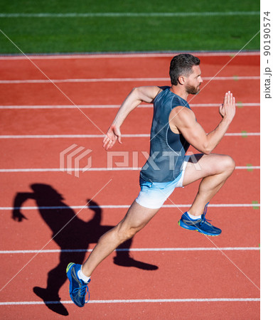 energetic athletic muscular man runner running on racetrack at outdoor stadium, endurance 90190574