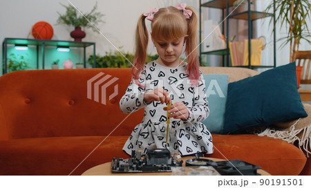 Little girl kid fixing repairing computer mainboard technology part, using magnifying glass at home Little girl kid fixing repairing computer mainboard technology part, using magnifying glass at home 90191501