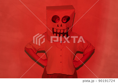 Portrait of unrecognizable person in Halloween mask made of paper bag standing with hands on hips in red light Portrait of unrecognizable person in Halloween mask made of paper bag standing with hands on hips in red light 90191724