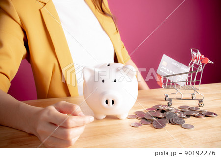 Close up. Young woman with white piggybank,coins & shopping cart or trolley. collecting points a credit card. Concept of saving money shopping in the store or online. E-commerce, Copy space. Close up. Young woman with white piggybank,coins & shopping cart or trolley. collecting points a credit card. Concept of saving money shopping in the store or online. E-commerce, Copy space. 90192276