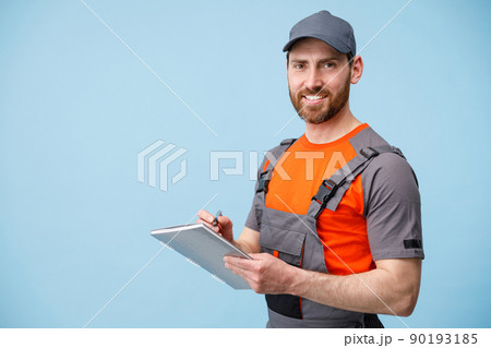 Smiling Delivery man in uniform holding tablet and taking work notes Smiling Delivery man in uniform holding tablet and taking work notes 90193185
