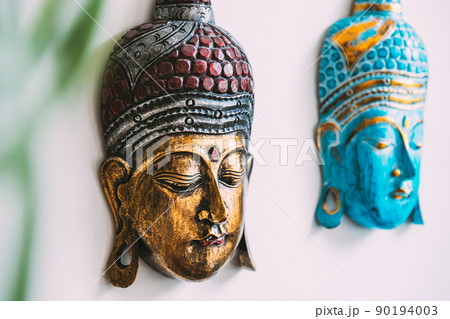 Close up of handmade souvenirs buddha mask on white background under branches. Details Close up of handmade souvenirs buddha mask on white background under branches. Details 90194003