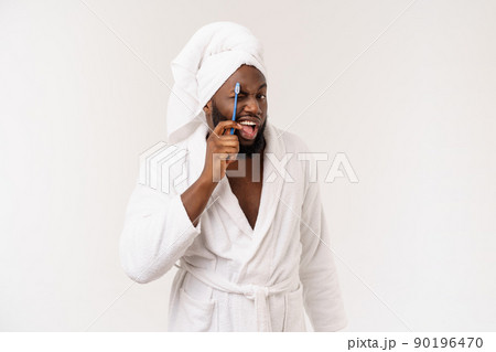 portrait of a happy young dark-anm brushing his teeth with black toothpaste on a white background. 90196470