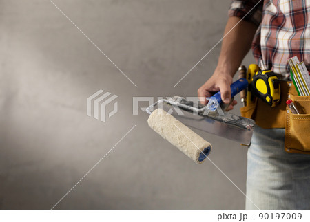 Construction worker man holding paint roller tool house room renovation. Male hand and construction tools Construction worker man holding paint roller tool house room renovation. Male hand and construction tools 90197009