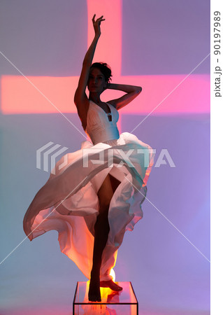 Beautiful young lady posing in a photo studio in a chic dress. Sexy model in bright colored spotlights. Beautiful young lady posing in a photo studio in a chic dress. Sexy model in bright colored spotlights. 90197989