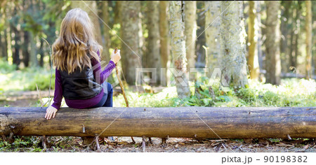 Young girl with long hair sitting on a tree log in autumn forest. Hiker woman resting. Young girl with long hair sitting on a tree log in autumn forest. Hiker woman resting. 90198382