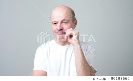 Smiling, handsome man touching his mustache twisting them Smiling, handsome man touching his mustache twisting them 90198666