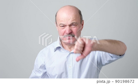 Mature caucasian man showing his dislike and disappointment with thumbs down 90198672