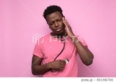 African man listening to his heart with stethoscope isolated on pink background. 90198700