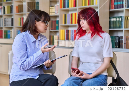 Psychologist, college counselor counseling teenage student in library, office Psychologist, college counselor counseling teenage student in library, office 90198732