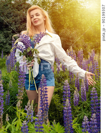Woman walks in the garden full of lupines Woman walks in the garden full of lupines 90199307