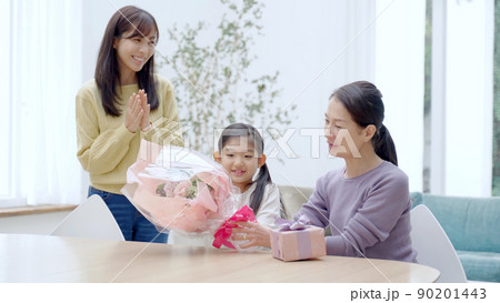 おばあちゃんにお花とプレゼントを渡す女の子 90201443