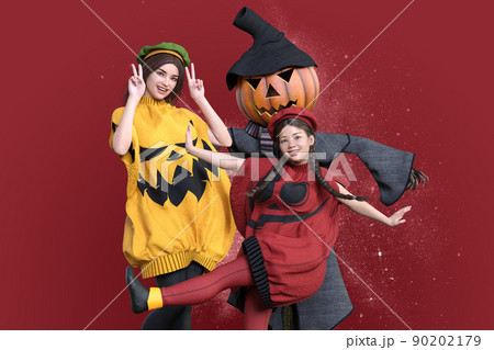 美人のお姉さんと三つ編みをした女の子がかぼちゃの衣装を着てカカシと一緒にハロウィンを楽しむ 90202179