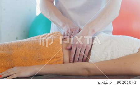 A young woman receiving a massage. Massaging the stomach. Side view 90205943