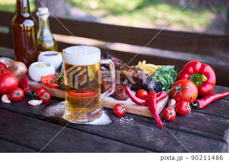 Barbecue pork ribs on wooden serving board on picnic table outdoors Barbecue pork ribs on wooden serving board on picnic table outdoors 90211486