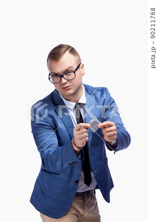 Young guy in a jacket, bow tie, glasses holds a condom in his hand. Isolated on white background 90211768