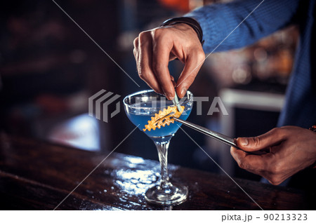 Charismatic tapster pouring fresh alcoholic drink into the glasses in the nightclub Charismatic tapster pouring fresh alcoholic drink into the glasses in the nightclub 90213323