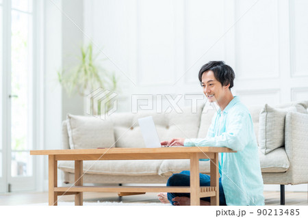 リビングでノートパソコンを操作する男性。 リビングでノートパソコンを操作する男性。 90213485