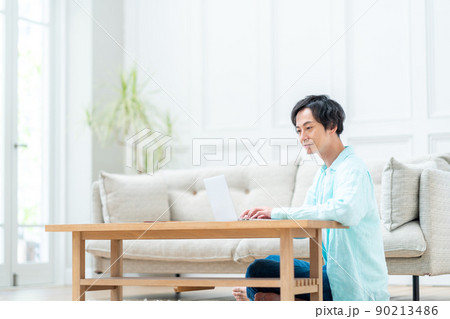 リビングでノートパソコンを操作する男性。 90213486