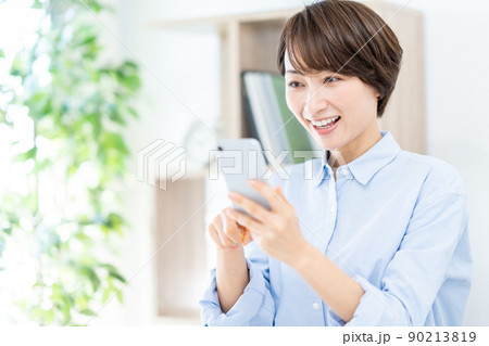 リビングでスマホを操作するミドル女性 90213819