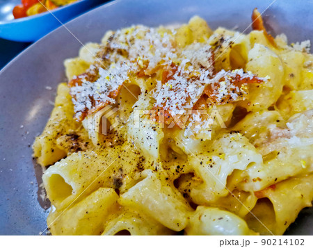 Penne pasta carbonara on white sauce with bacon and extra topping cheese served on blue plate Penne pasta carbonara on white sauce with bacon and extra topping cheese served on blue plate 90214102