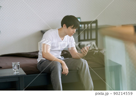 寝起きにスマホを見る若い男性 寝起きにスマホを見る若い男性 90214559
