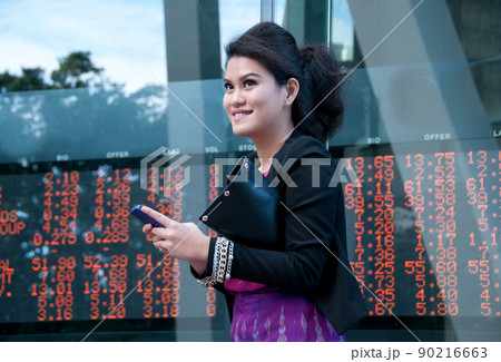 Business woman trade stock on mobile near exchange board 90216663
