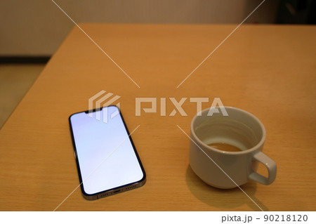 スマートフォンを見ながら珈琲を楽しむひととき 90218120