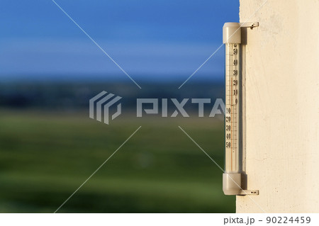 Thermometer celsius showing warm temperature on blurred green background. Weather forecast concept. Thermometer celsius showing warm temperature on blurred green background. Weather forecast concept. 90224459