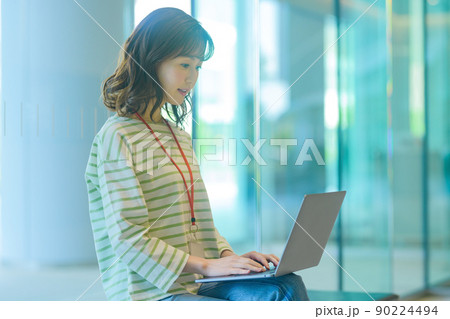 オフィスのエントランスでパソコンを操作する若いエンジニアの女性撮影協力：LINK FOREST 90224494