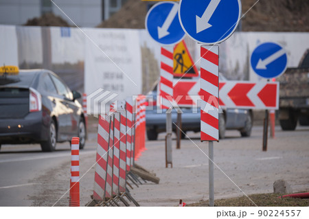 Roadworks warning traffic signs of construction work on city street and slowly moving cars Roadworks warning traffic signs of construction work on city street and slowly moving cars 90224557