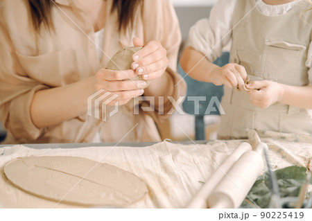 Woman and girl kneading clay. Family make art product at table in pottery workshop. Mother with daughter. Woman and girl kneading clay. Family make art product at table in pottery workshop. Mother with daughter. 90225419