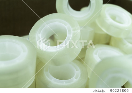 Small narrow rollers of transparent stationery tape for dispensers. Heap sticky tape. Selective focus 90225806
