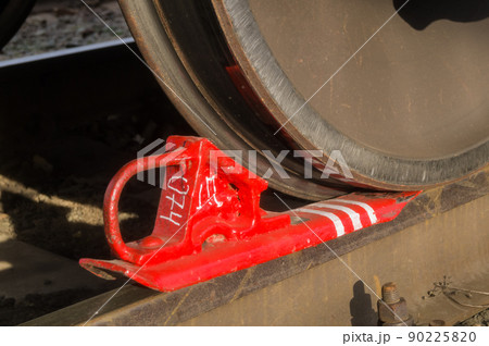 Red railway brake shoe under the iron wheel of freight cars on rail. Parking brake device. Selective focus 90225820