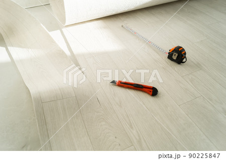Laying new linoleum on the floor in the room. Tools for mounting and trimming linoleum. Measuring tape measure, stationery knife, marker handle. Selective focus 90225847