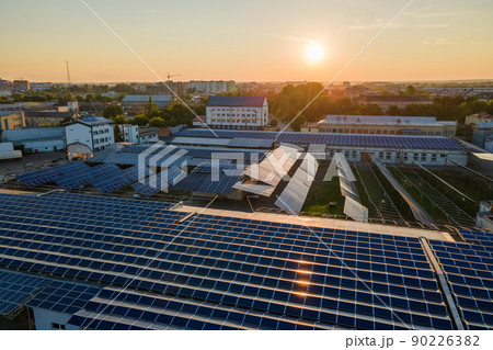 Aerial view of solar power plant with blue photovoltaic panels mounted on industrial building roof for producing green ecological electricity. Production of sustainable energy concept 90226382