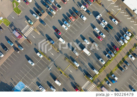 Aerial view of many colorful cars parked on parking lot with lines and markings for parking places and directions Aerial view of many colorful cars parked on parking lot with lines and markings for parking places and directions 90226479