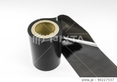 Black thermal transfer ribbon - TTR. Wax thermo ribbon on cardboard reel for barcode. Supply material for printing industry. Selective focus, isolated on white Black thermal transfer ribbon - TTR. Wax thermo ribbon on cardboard reel for barcode. Supply material for printing industry. Selective focus, isolated on white 90227537
