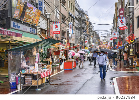 [東京・巣鴨] 雨の日に巣鴨地蔵通り商店街で並ぶ屋台を傘を指しながら楽しむ人々。 90227934