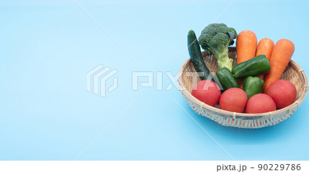 青背景の緑黄色野菜が入った籠と左側のコピースペース 90229786