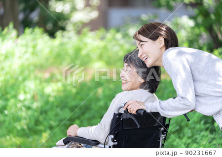 公園で話をする介護士と車椅子のシニア女性 90231667