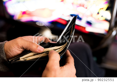 パチンコ屋で財布から1万円札を投資する様子 パチンコ屋で財布から1万円札を投資する様子 90232551