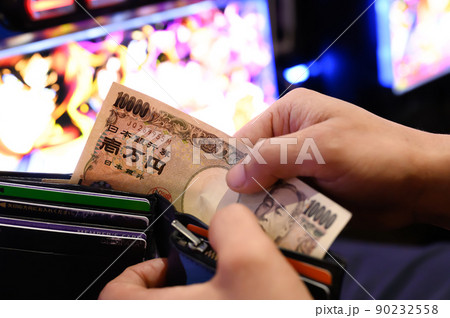 パチンコ屋で財布から1万円札を投資する様子 90232558