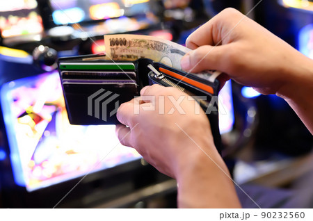 パチンコ屋で財布から1万円札を投資する様子 パチンコ屋で財布から1万円札を投資する様子 90232560