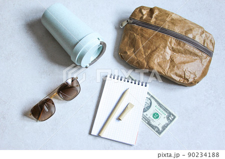 Pen, bag, cardboard cup made of recycled paper. Travel composition with sunglasses and dollars. Eco friendly modern objects from ecological biomaterials. Pen, bag, cardboard cup made of recycled paper. Travel composition with sunglasses and dollars. Eco friendly modern objects from ecological biomaterials. 90234188