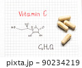 Chemical formula of Vitamin C and some pills on the white paper background. Close-up. Vitamins for health. 90234219