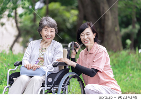 公園で会話する介護士と車椅子のシニア女性 公園で会話する介護士と車椅子のシニア女性 90234349