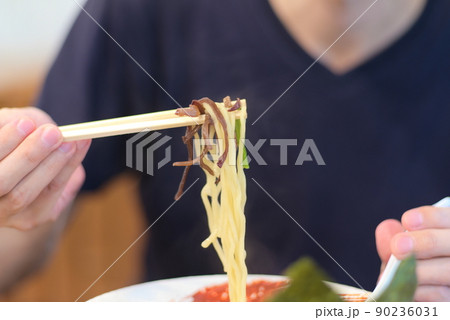 家系ラーメンを食べようと箸で掬っている様子 90236031