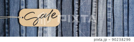 Denim. Blue jeans background. Sale - handwritten inscription on a paper label. 90238296