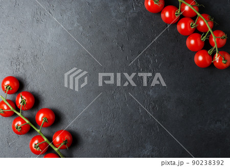 Ripe red tomatoes on a green branch. Vitamin-rich vegetables. Dark background. Flat lay. Copy space 90238392